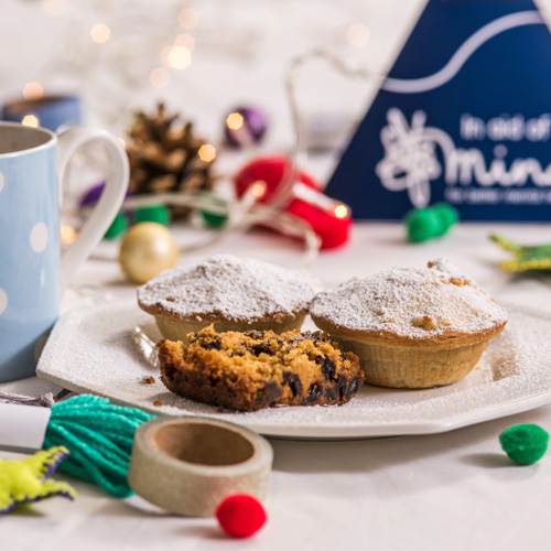 Mince pies and Christmas cake on plate with donation box 