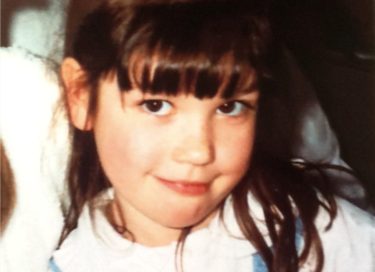 young female with long dark hair and full fringe smiling