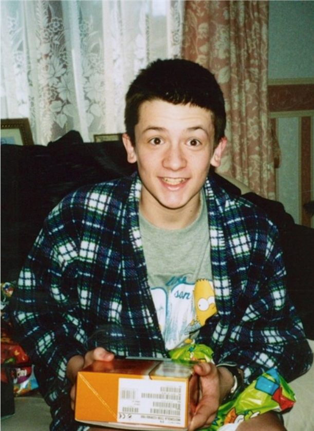 young male in dressing gown, beaming, holding a gift