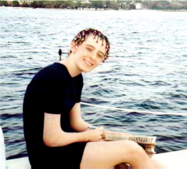 Female sitting, smiling, with water behind