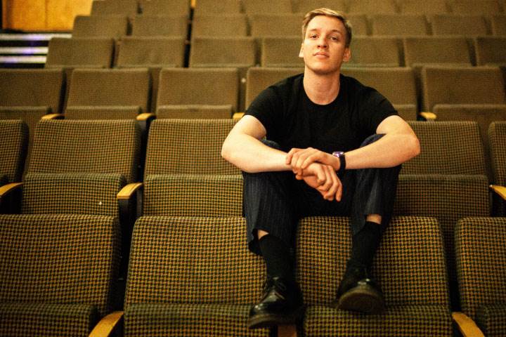 George Ezra sitting on back of chair at concert venue