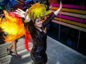 Smiling woman wearing a brightly coloured head piece and dancing