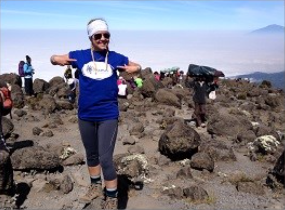 Female pointing at her Mind branded top and standing on a mountain with rocky terrain