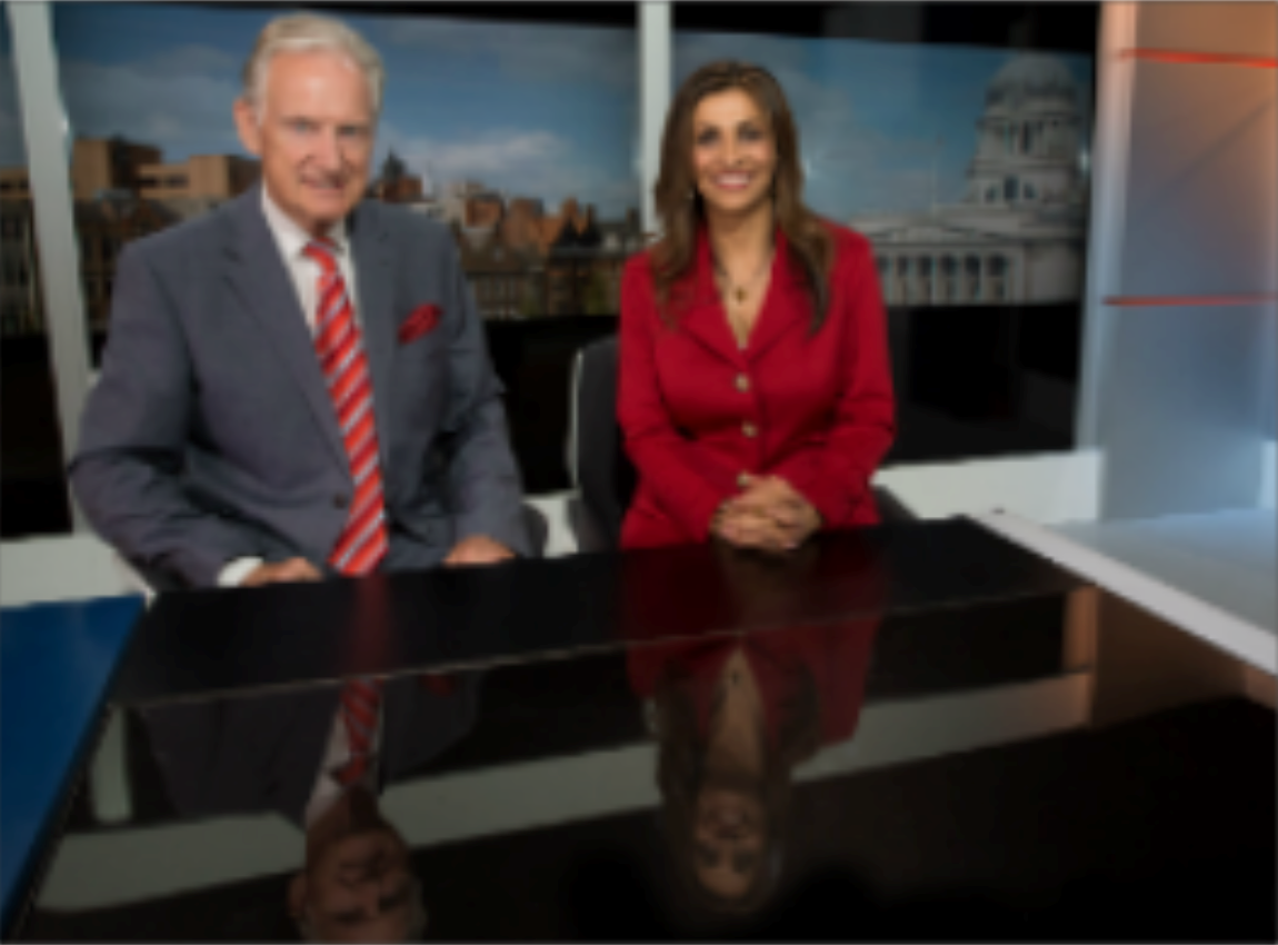 2 news presenters behind the desk on set