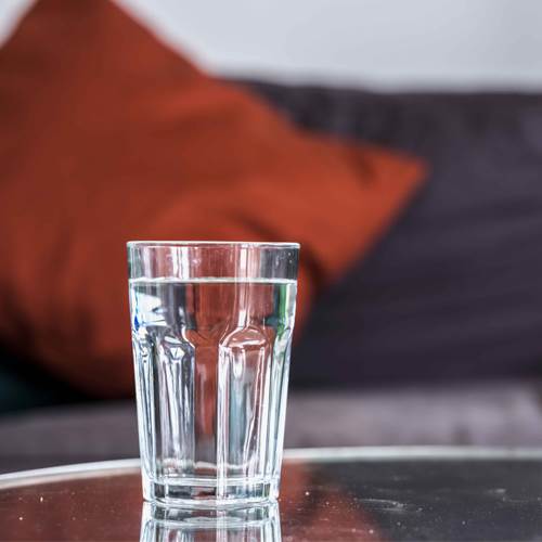Glass of water on table in home, in front of sofa