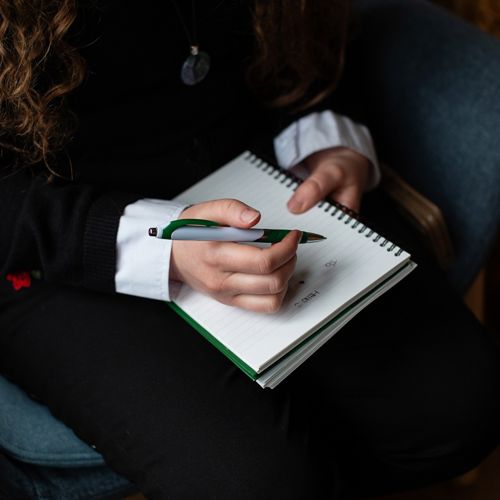 Close Up Of Person Writing In Note Pad