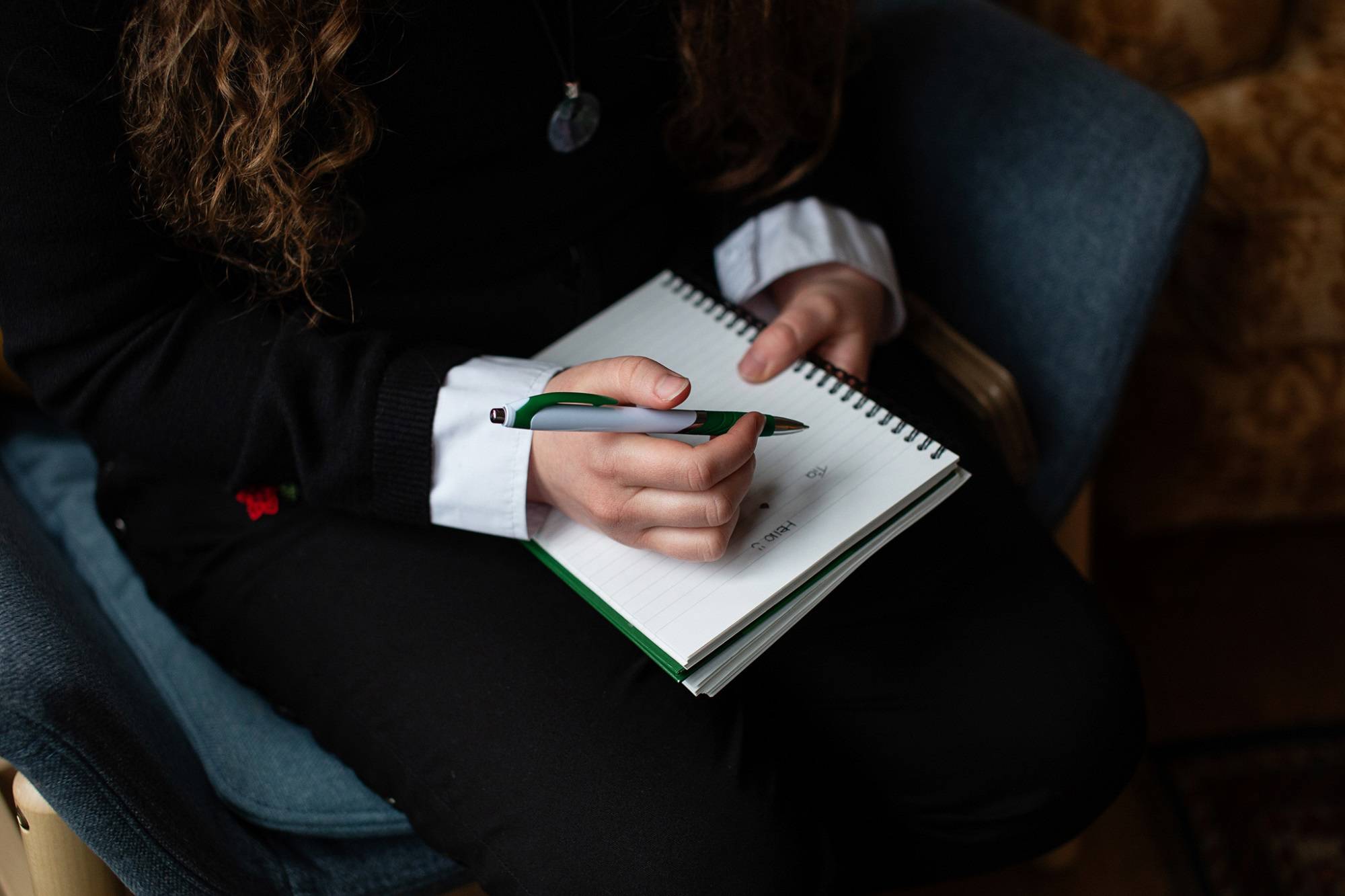 Close Up Of Person Writing In Note Pad