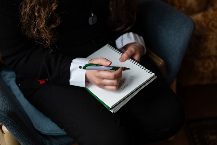 Close Up Of Person Writing In Note Pad