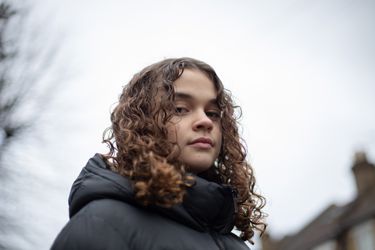 Close Up Of Teen Girl Looking Down At Camera In Street