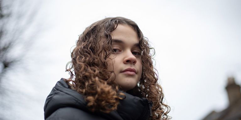 Close Up Of Teen Girl Looking Down At Camera In Street