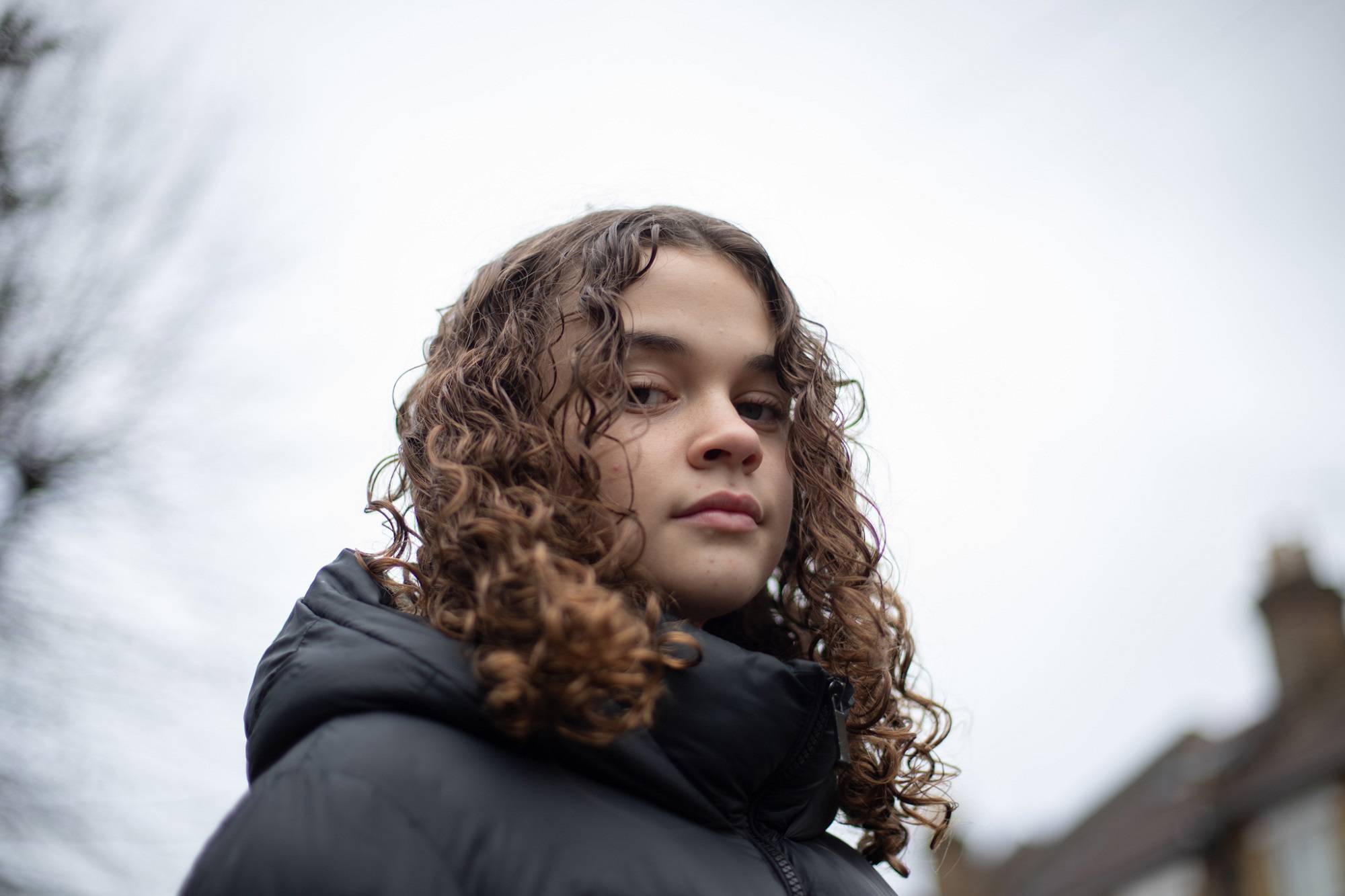 Close Up Of Teen Girl Looking Down At Camera In Street