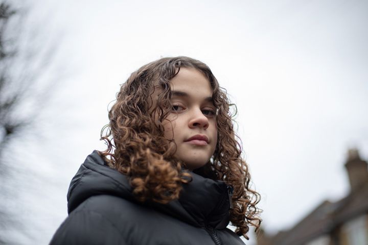 Close Up Of Teen Girl Looking Down At Camera In Street