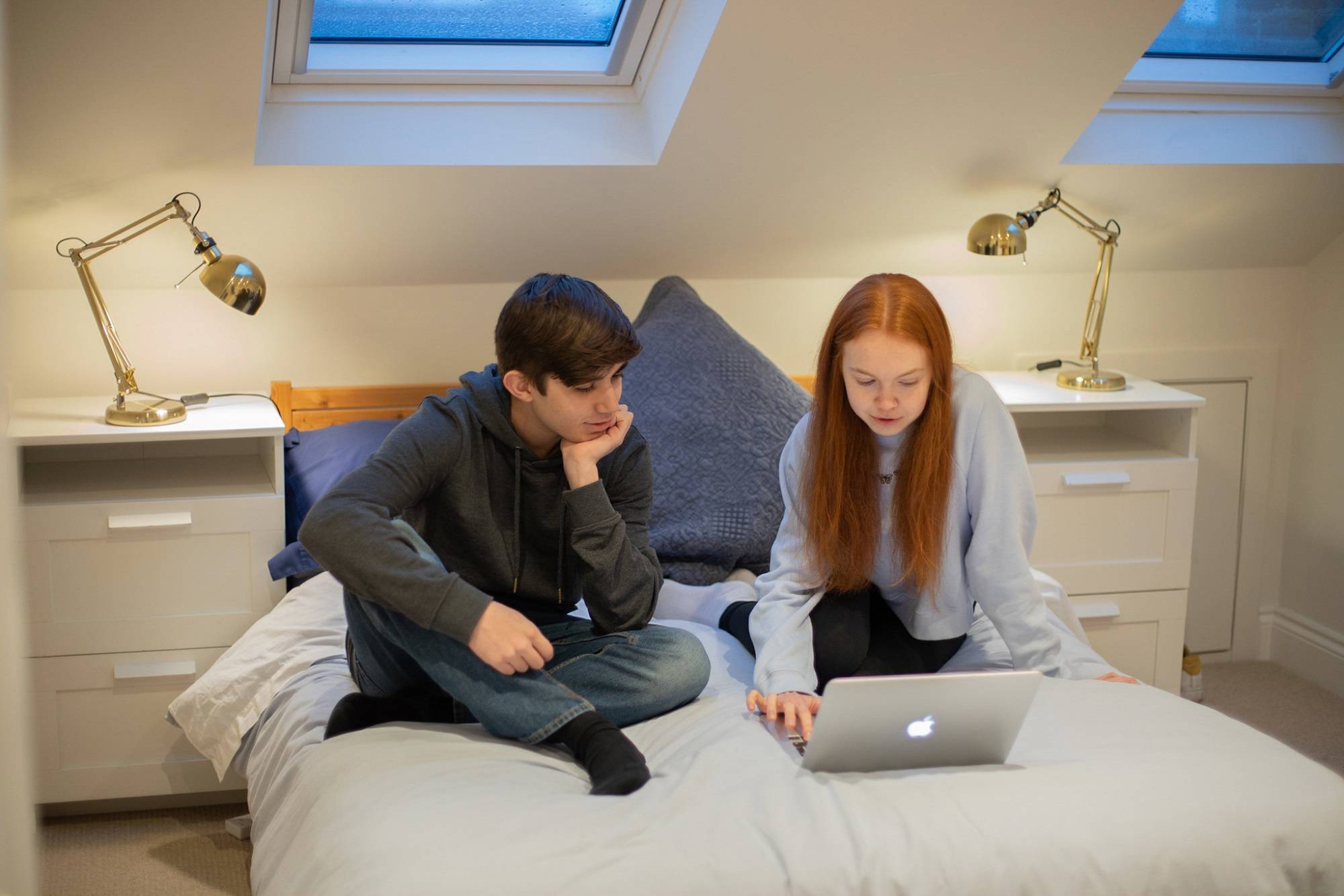 Teen Boy Discussing Laptop Content With Teen Girl On Bed