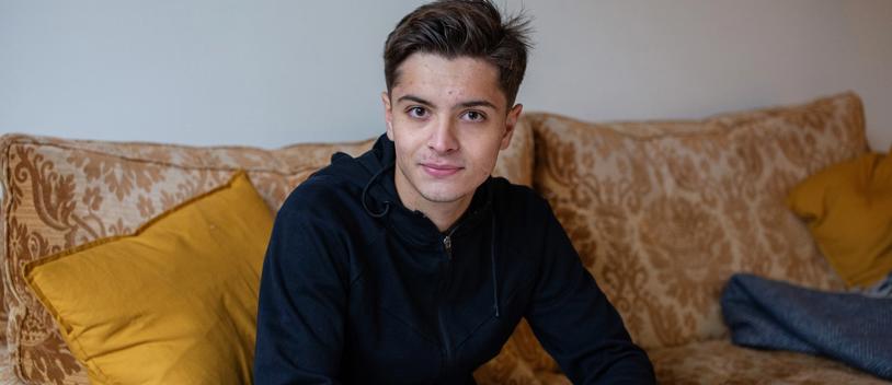 Teen Boy Looks At Camera Smiling While Using Phone