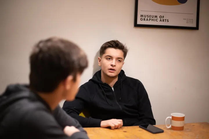 Teen Boy Talking To Other Teen Boy With Tea At A Table Teen Boy Talking To Other Teen Boy With Tea At A Table