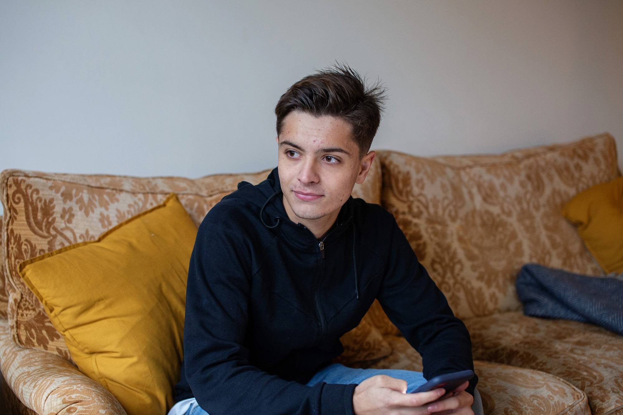 Teen Boy With Phone In Hand On Sofa