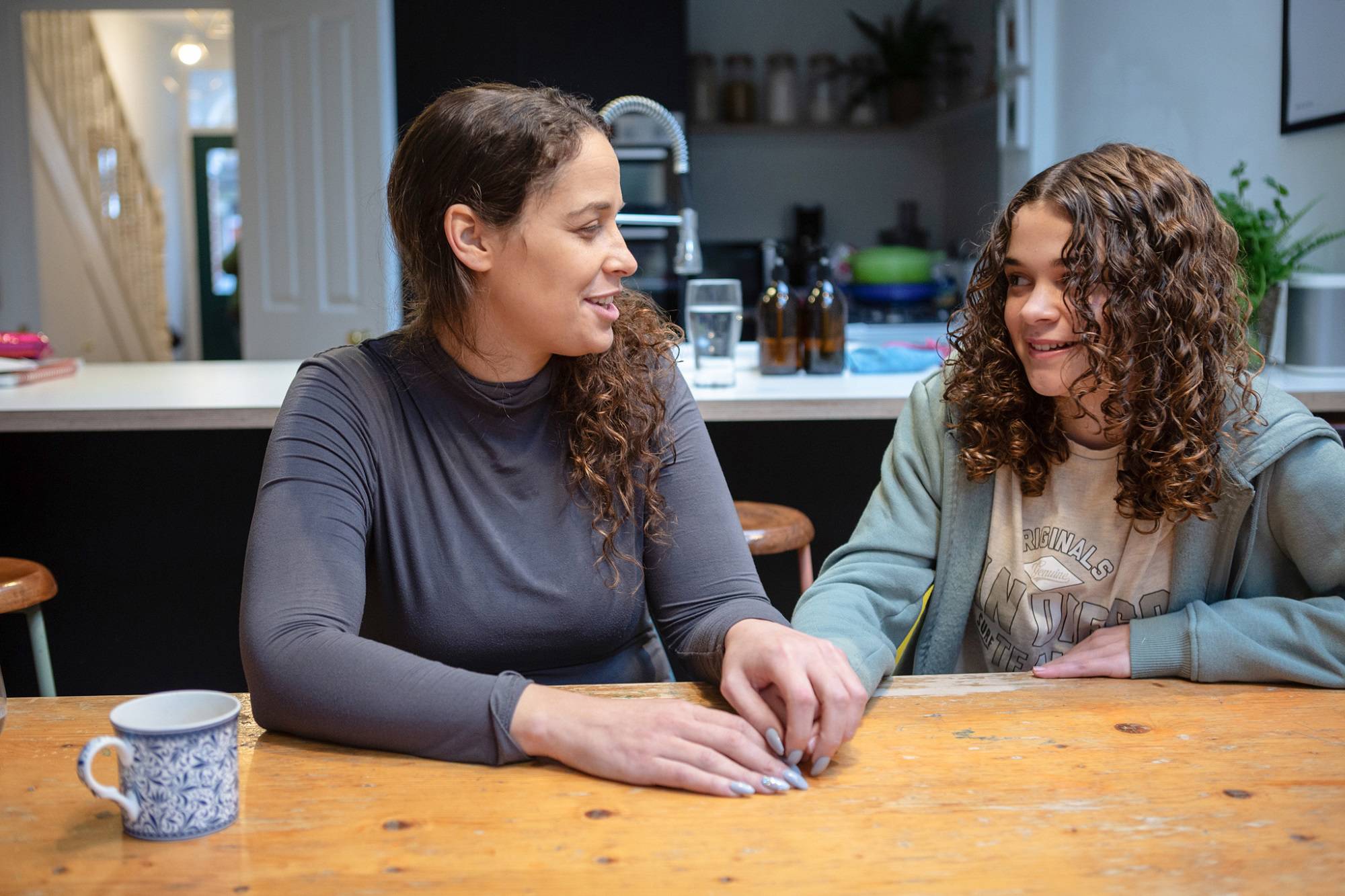 Teen Girl And Woman Chatting And Smiling At Table