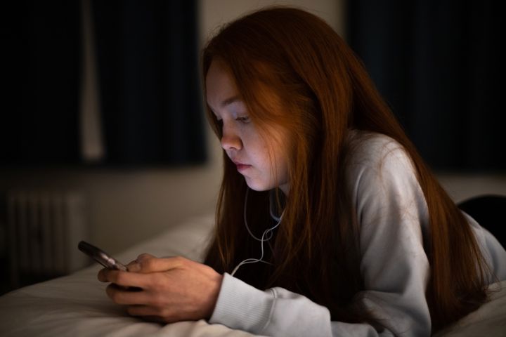 Teen Girl Looking At Phone With Neutral Expression