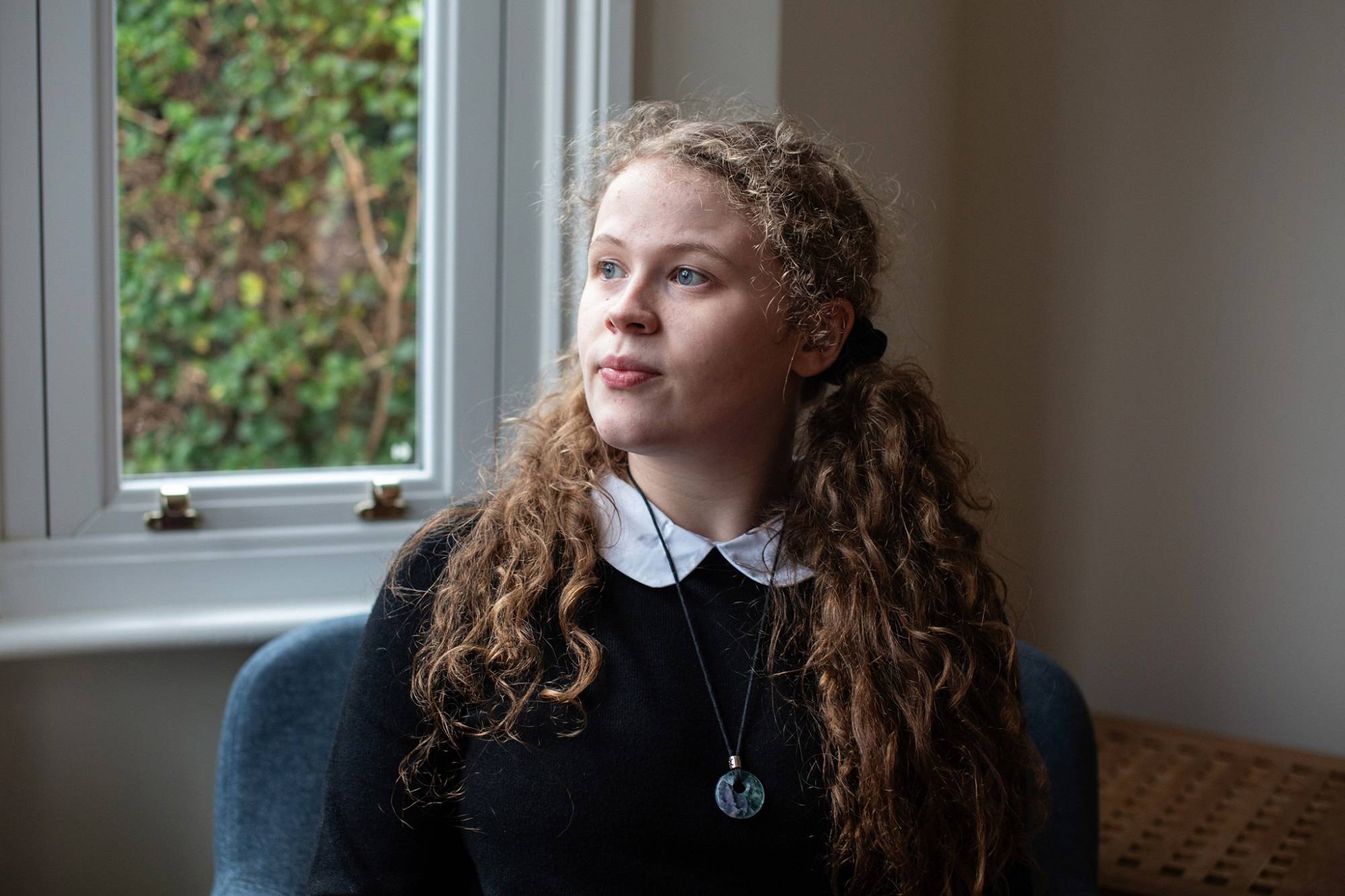 Teen Girl Looks Serious While Looking To Left Sat In Chair