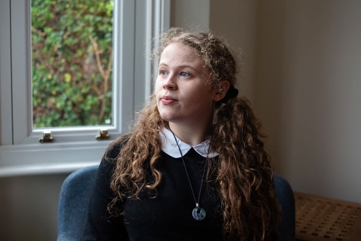 Teen Girl Looks Serious While Looking To Left Sat In Chair