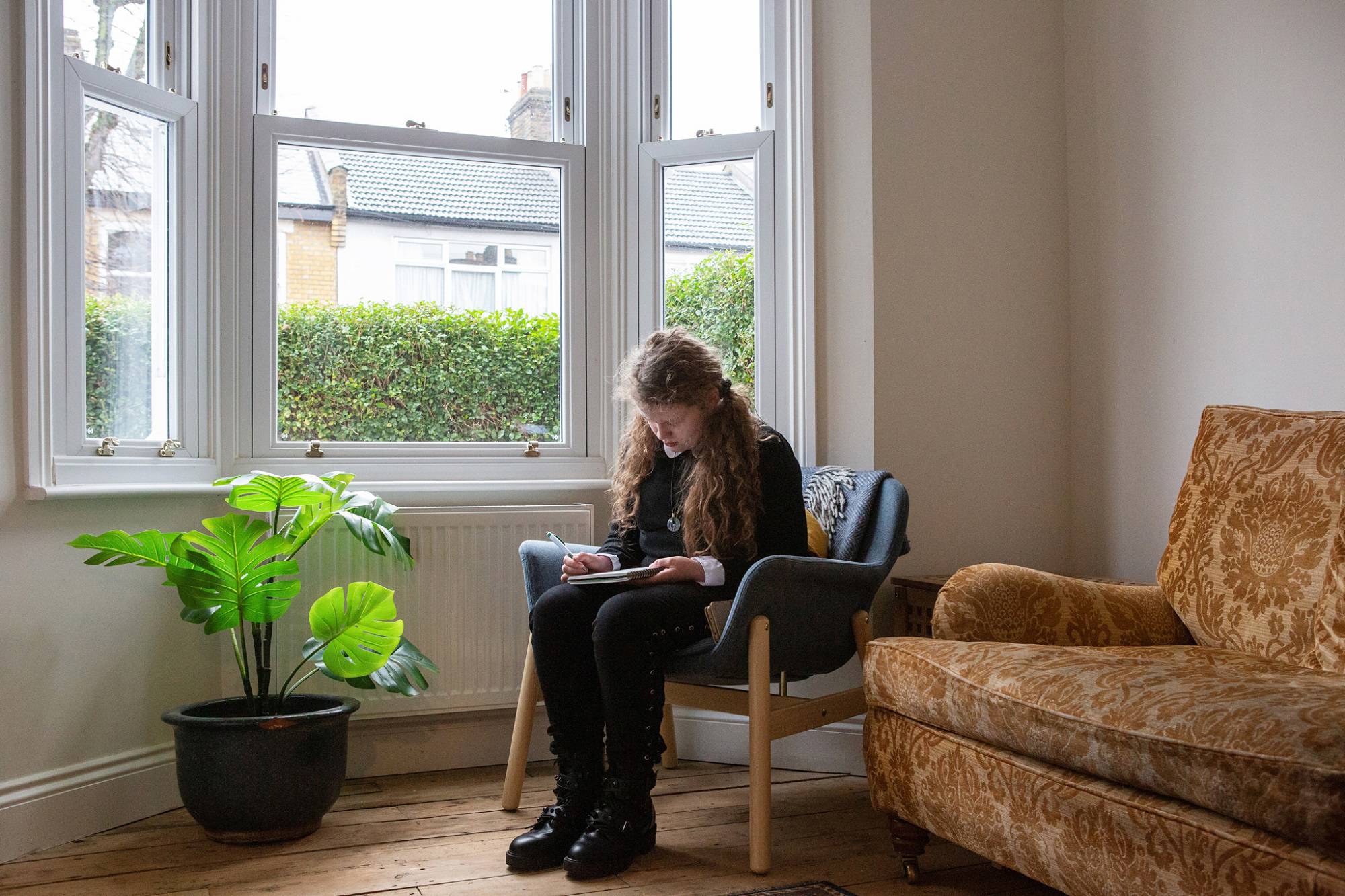 Teen Girl Sits In Chair Writing