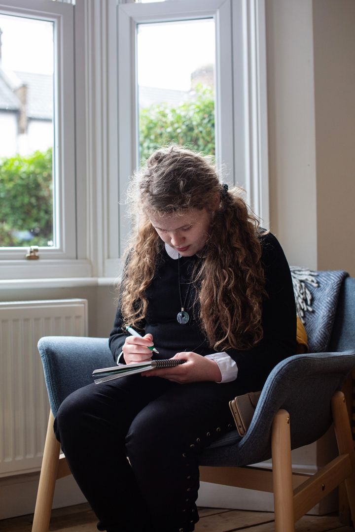 Teen Girl Sits Writing Close Up