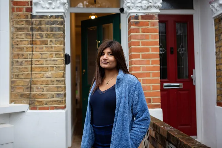 Teen Girl Stands In Front Of House Looking At Camera