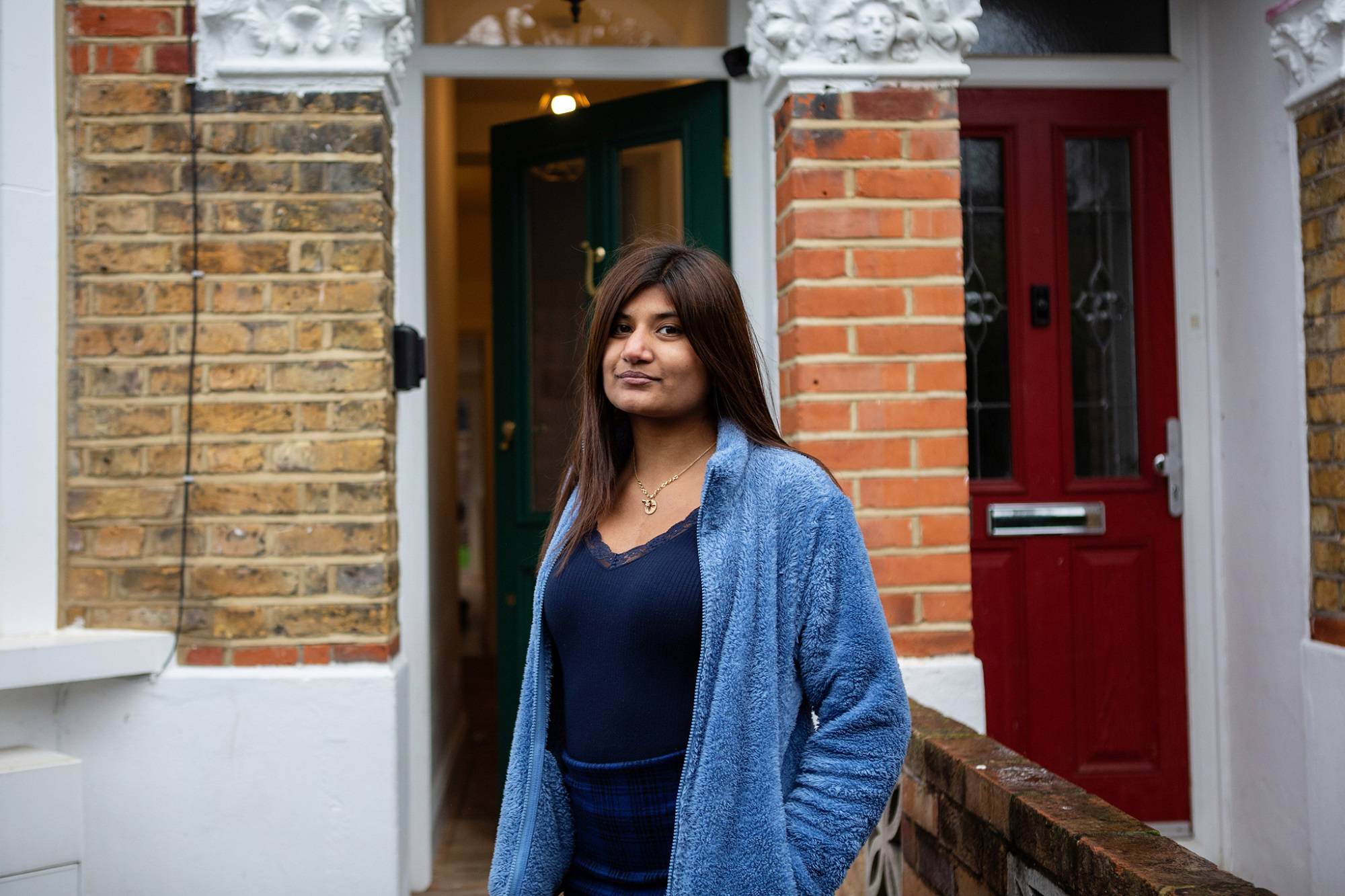 Teen Girl Stands In Front Of House Looking At Camera