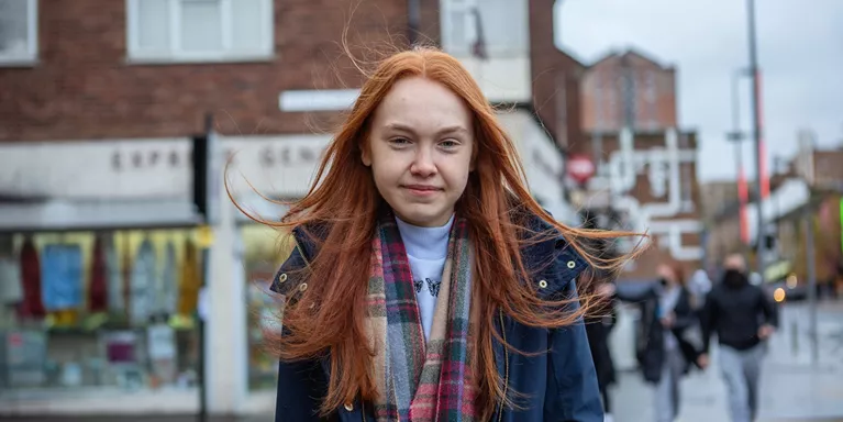 Teen Girl Stands In Town Centre Smiling