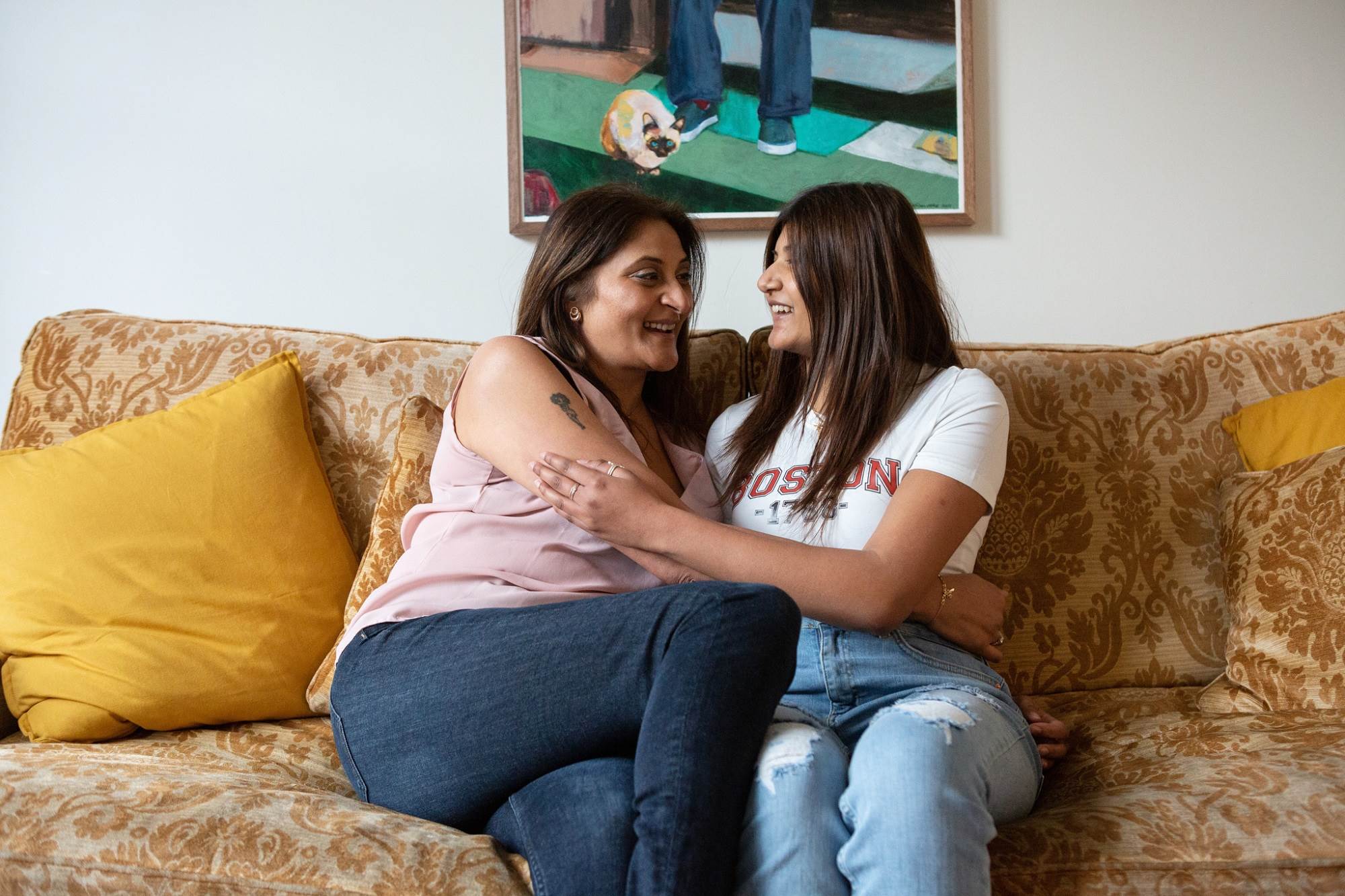 Woman And Teen Girl Hug On Sofa While Smiling