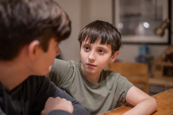 Young Boy Looking At Older Boy Sat Down
