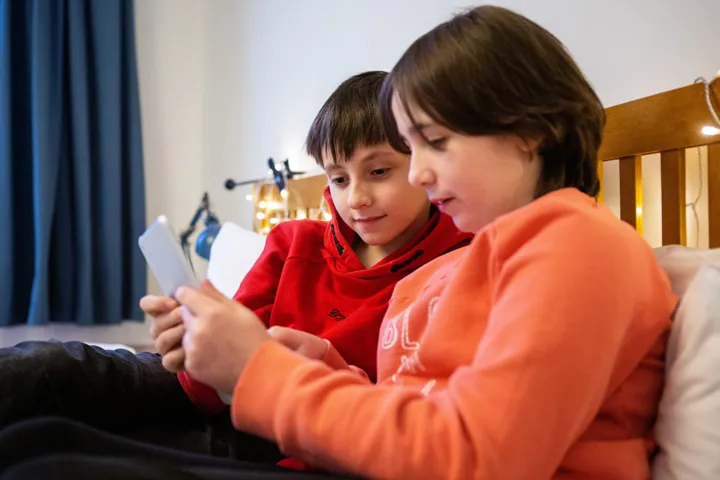 Young Boys Looking At Mobile Content Smiling Sat On Bed Young Boys Looking At Mobile Content Smiling Sat On Bed