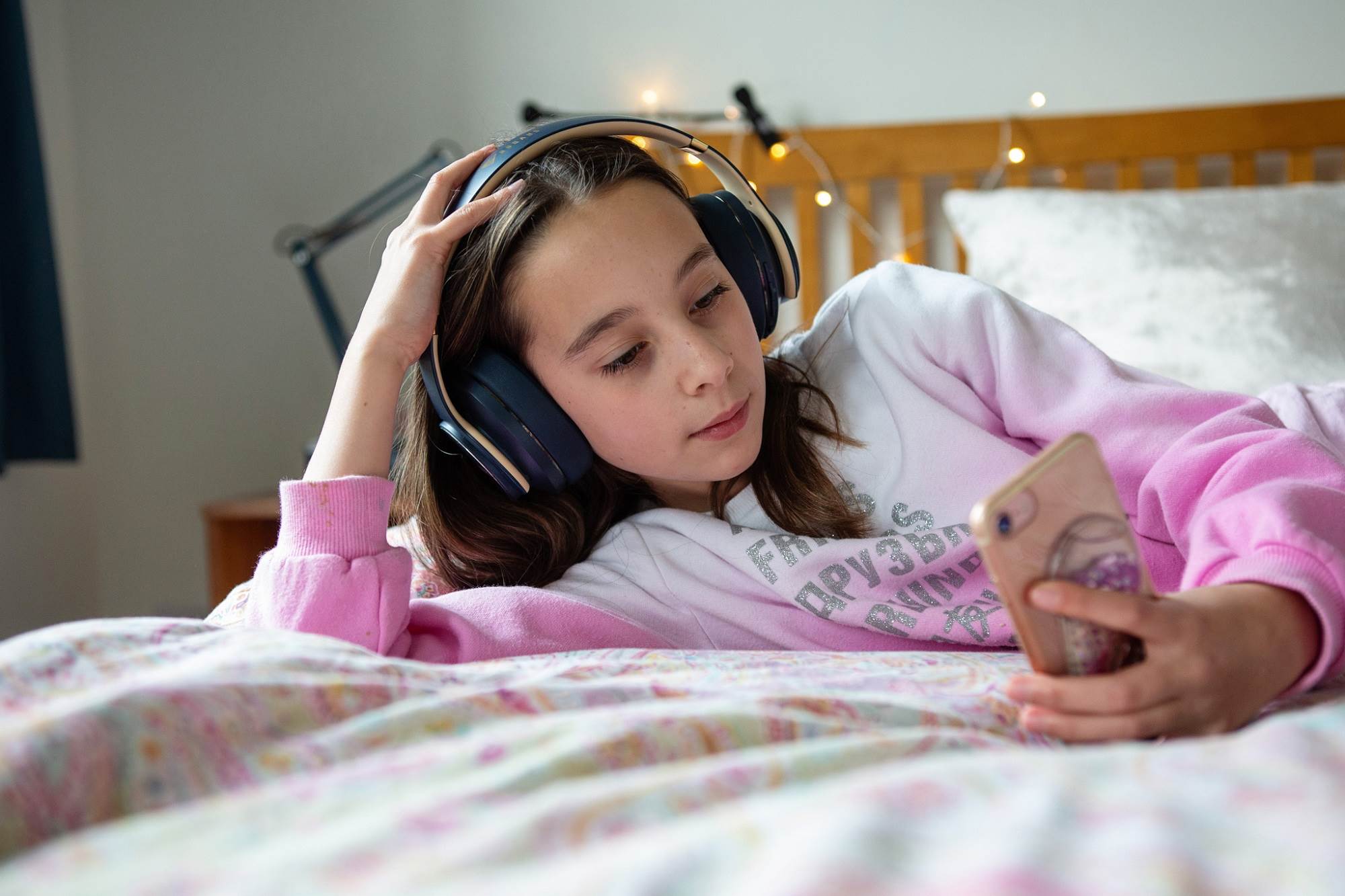 Young Girl Listens To Music On Phone While Reading Online Content