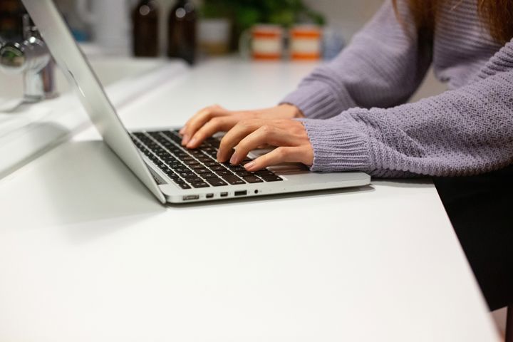 Young Person In Lavender Jumper Typing On Laptop