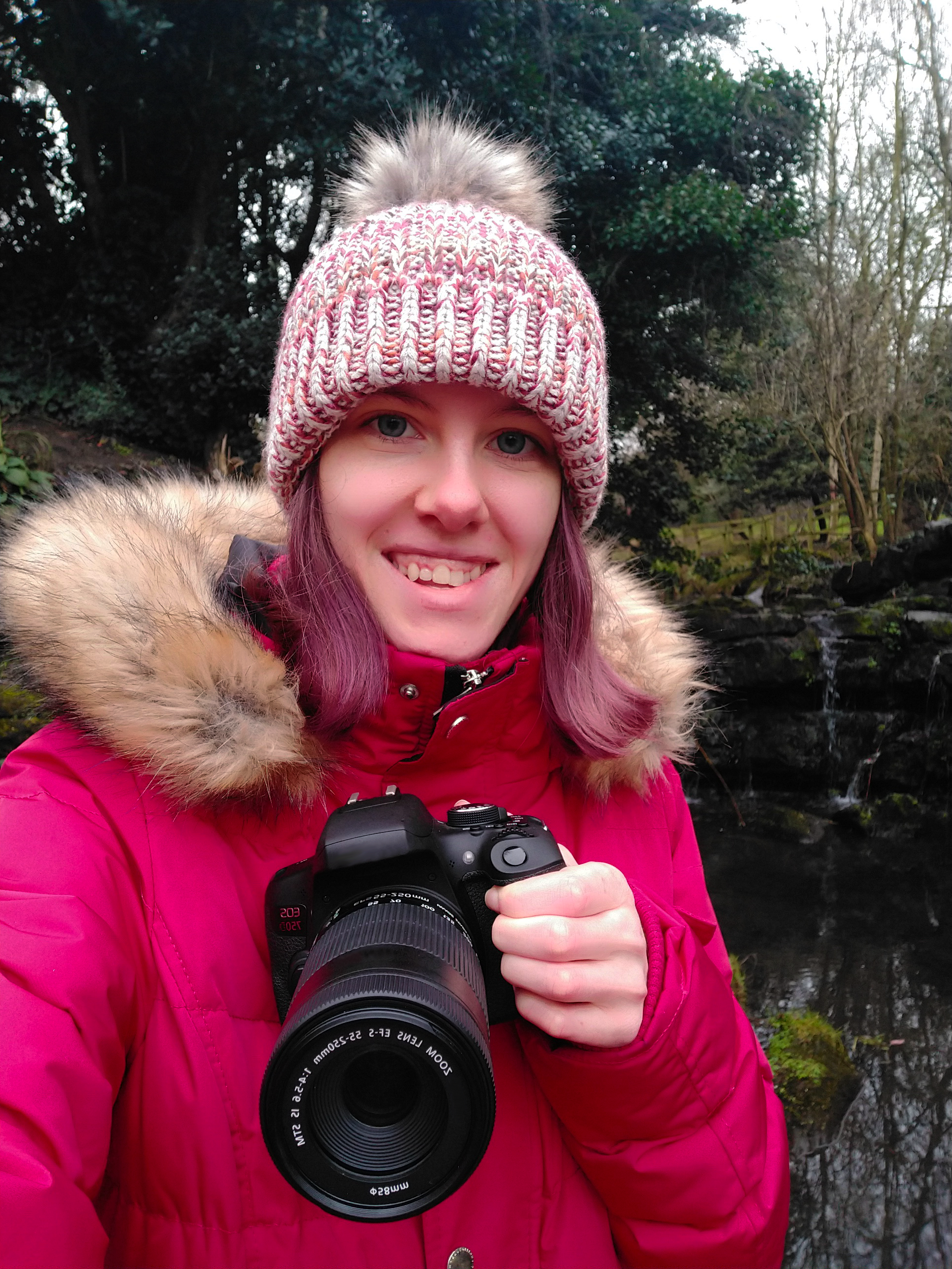 young white women in pink hat holds a camera