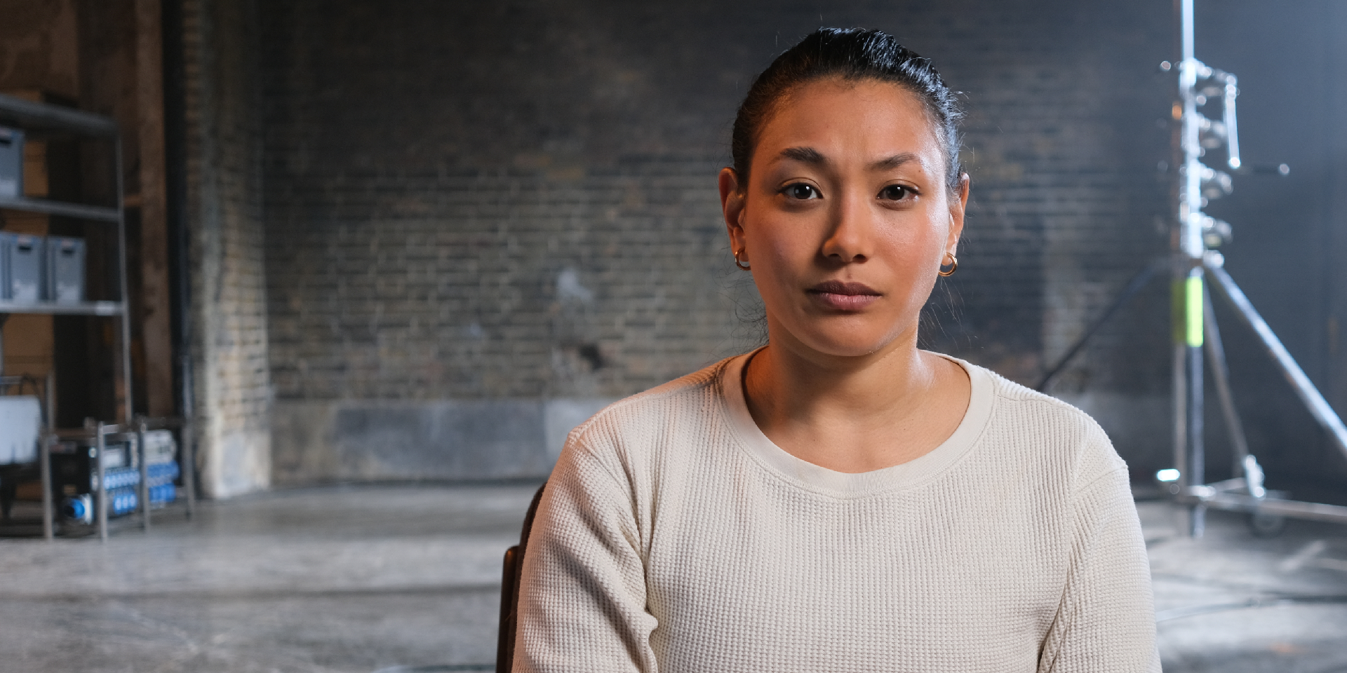 Woman looks directly to camera, background of a empty tv set.