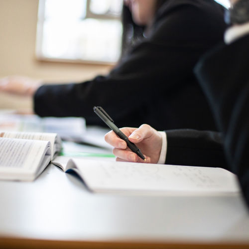 Student sat at desk Writing And Reading