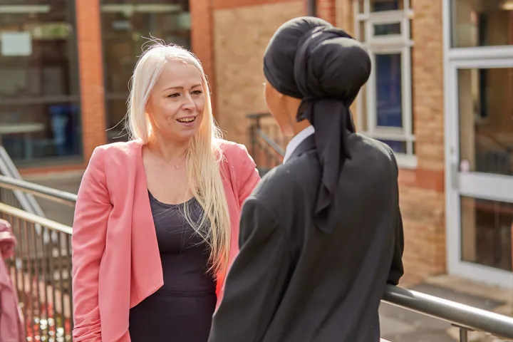 Teacher And Young Person Chatting Outside School