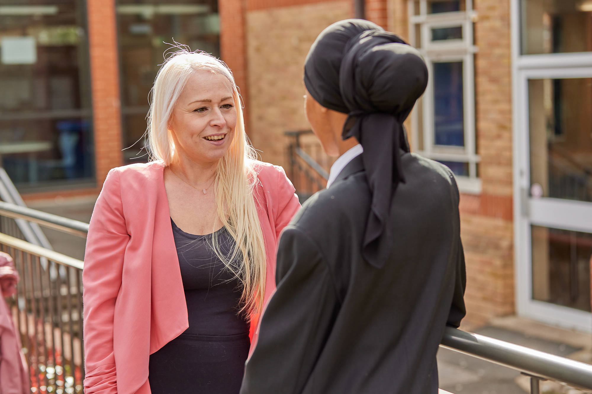 Teacher And Young Person Chatting Outside School