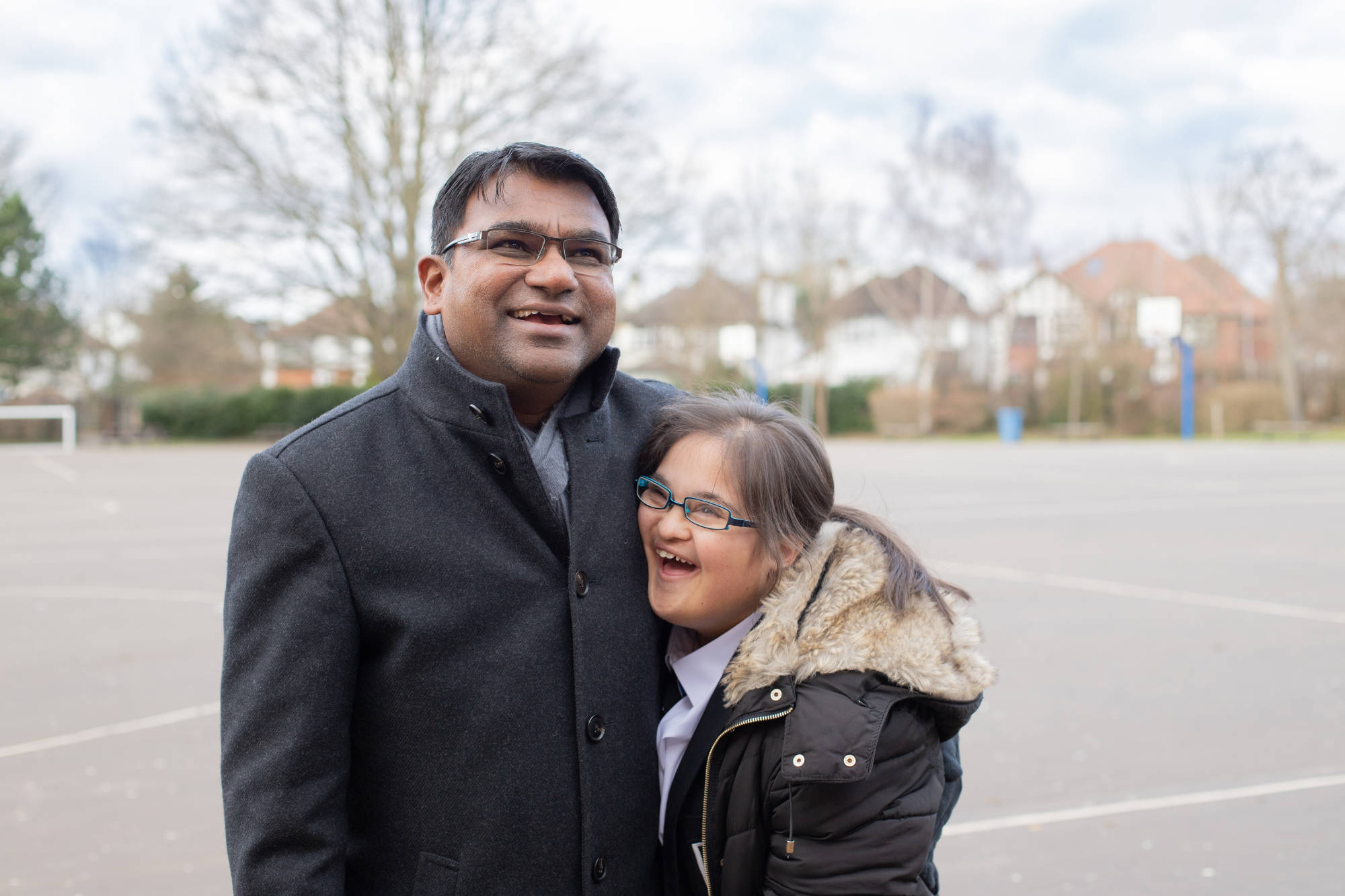 Teacher And Young Person Hugging In Playground