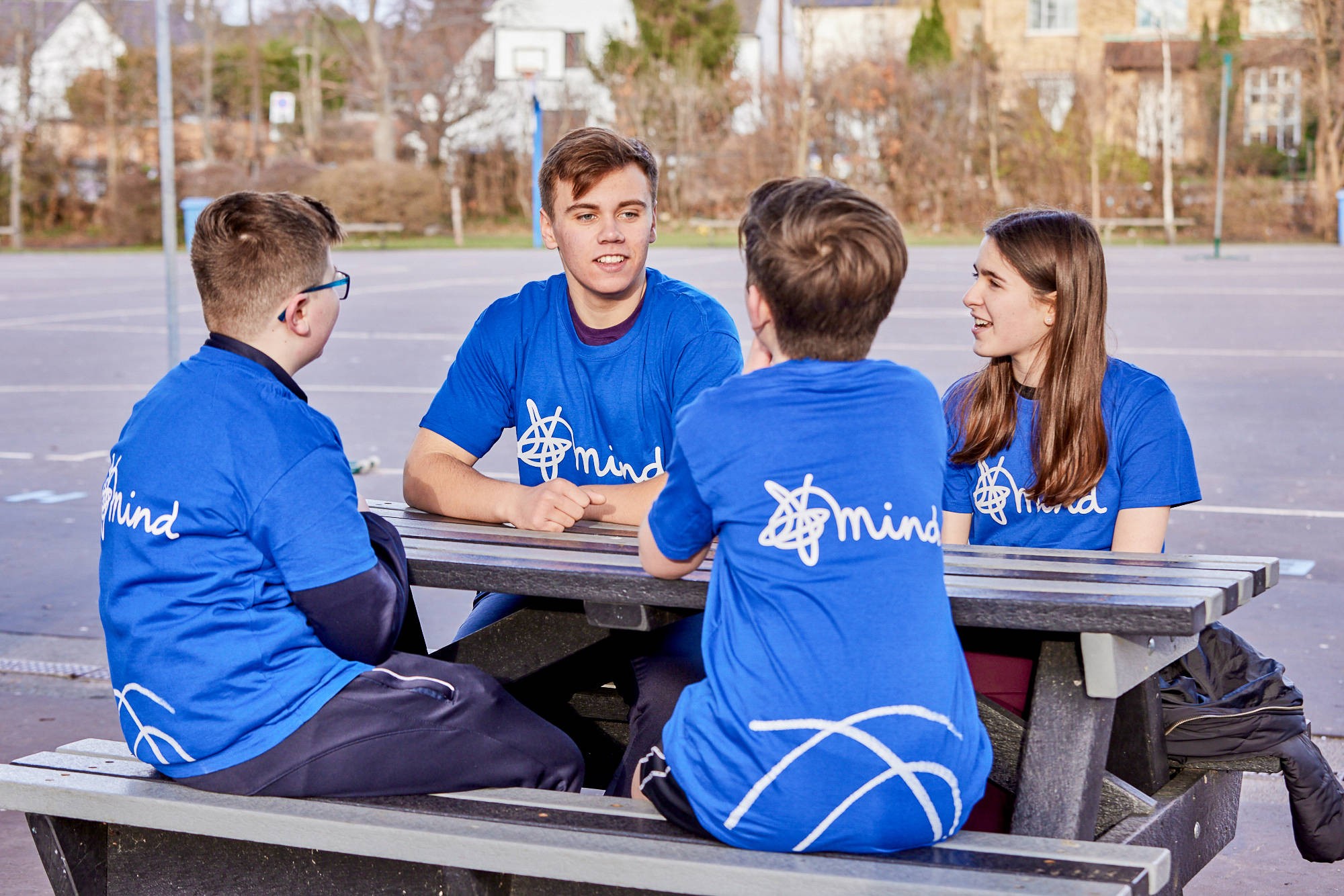 Young People Chatting At A Picnic Bench In Mind Tshirts In A Playground