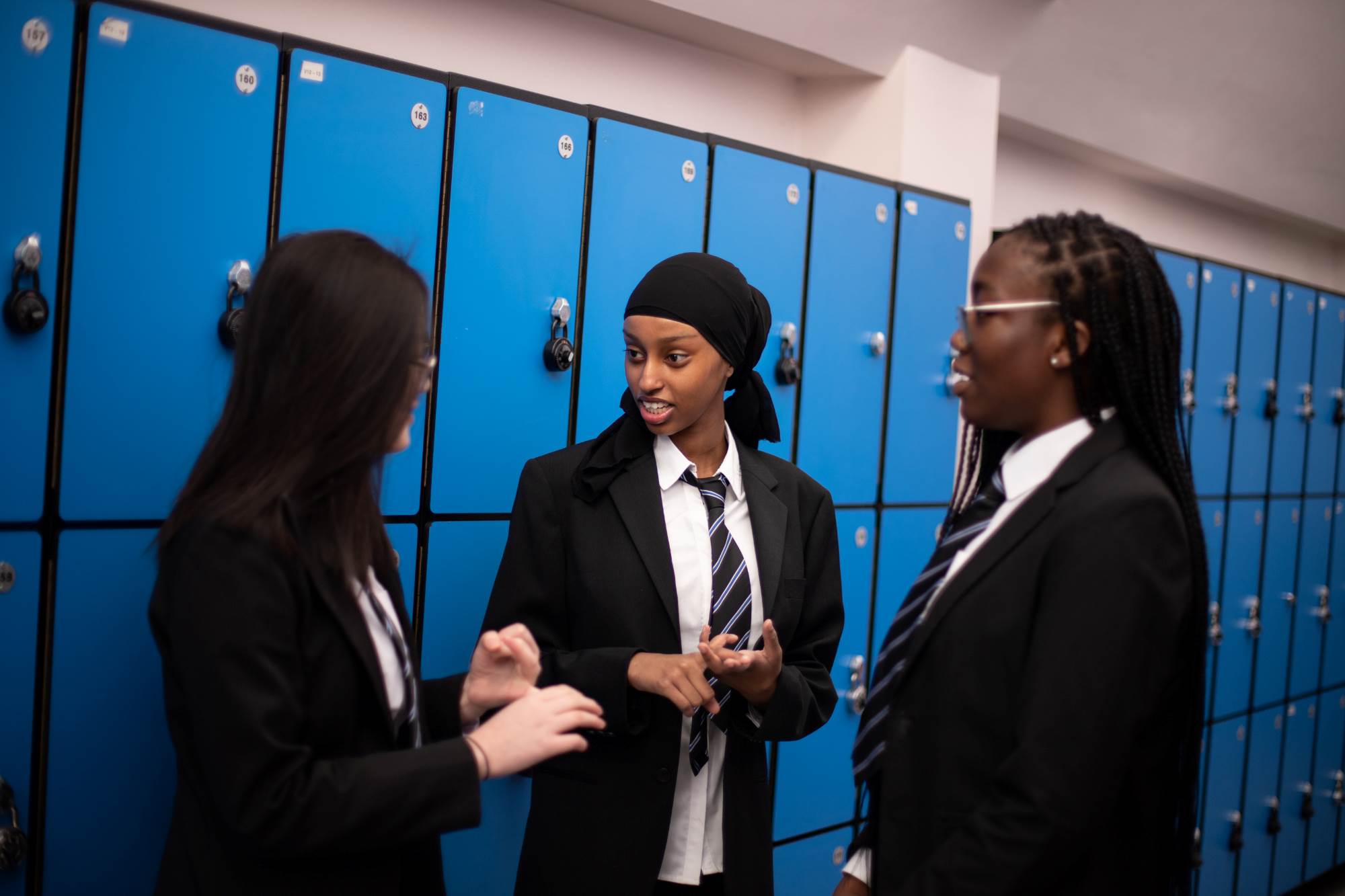 Young People Chatting In Front Of Lockers At School