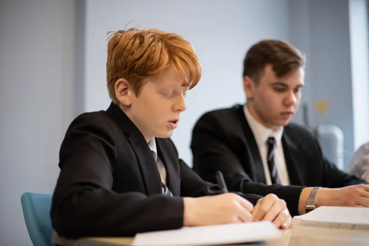 Young People Writing At A Desk