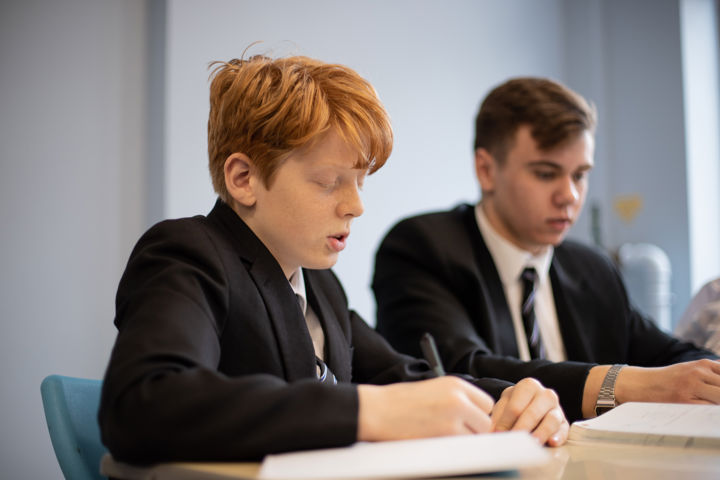 Young People Writing At A Desk