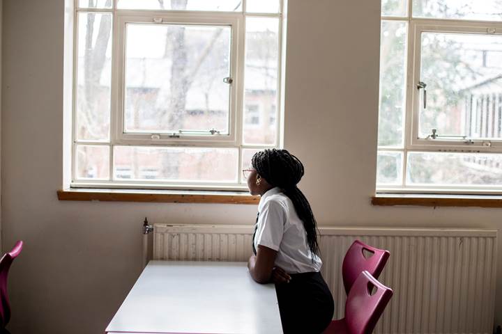 Young Person Sat At Desk Looking Out The Window