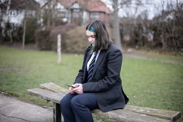 Young Person Sat On Bench Texting