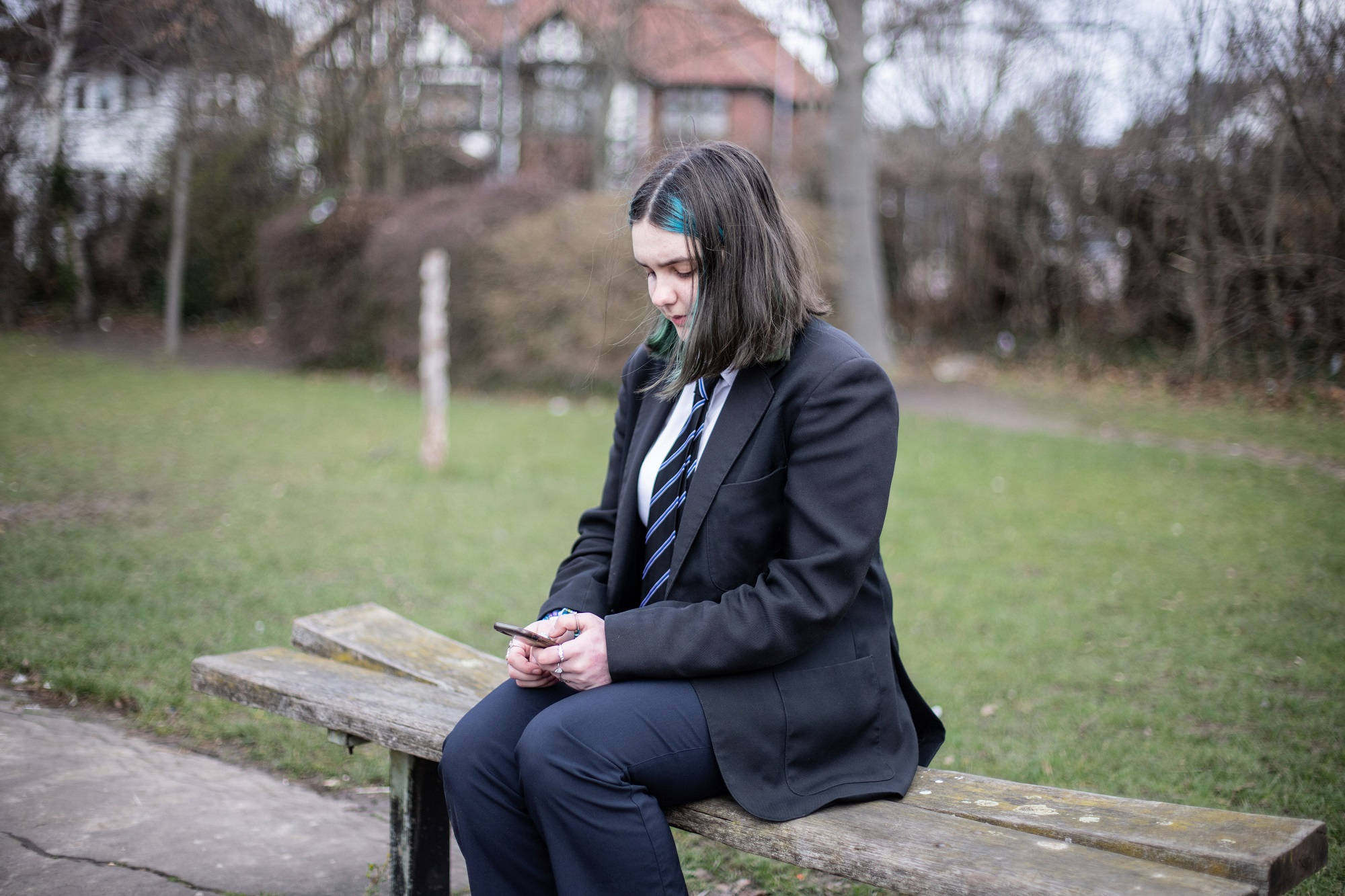 Young Person Sat On Bench Texting