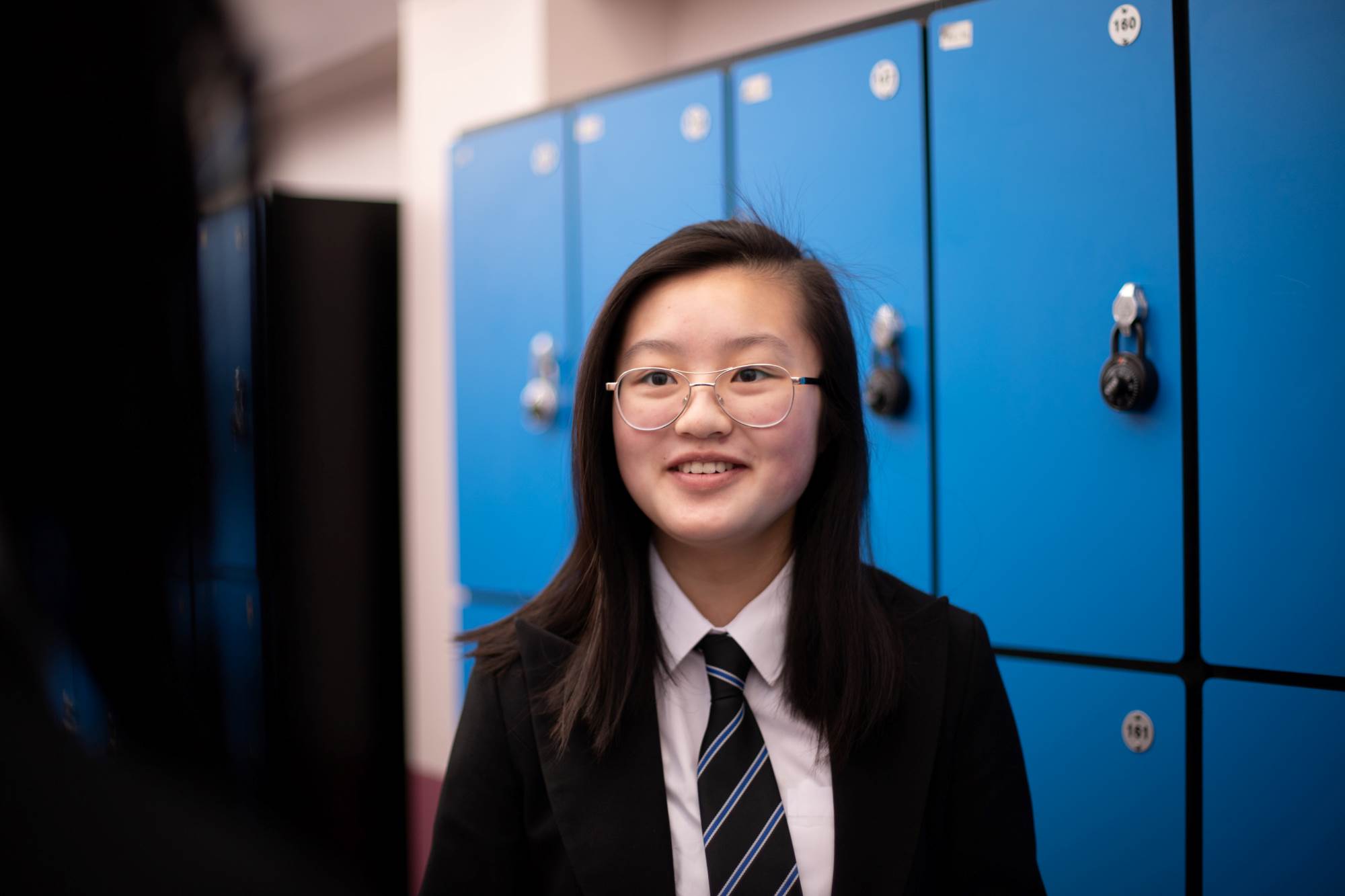 Young Person Smiling At The Camera In Front Of Lockers