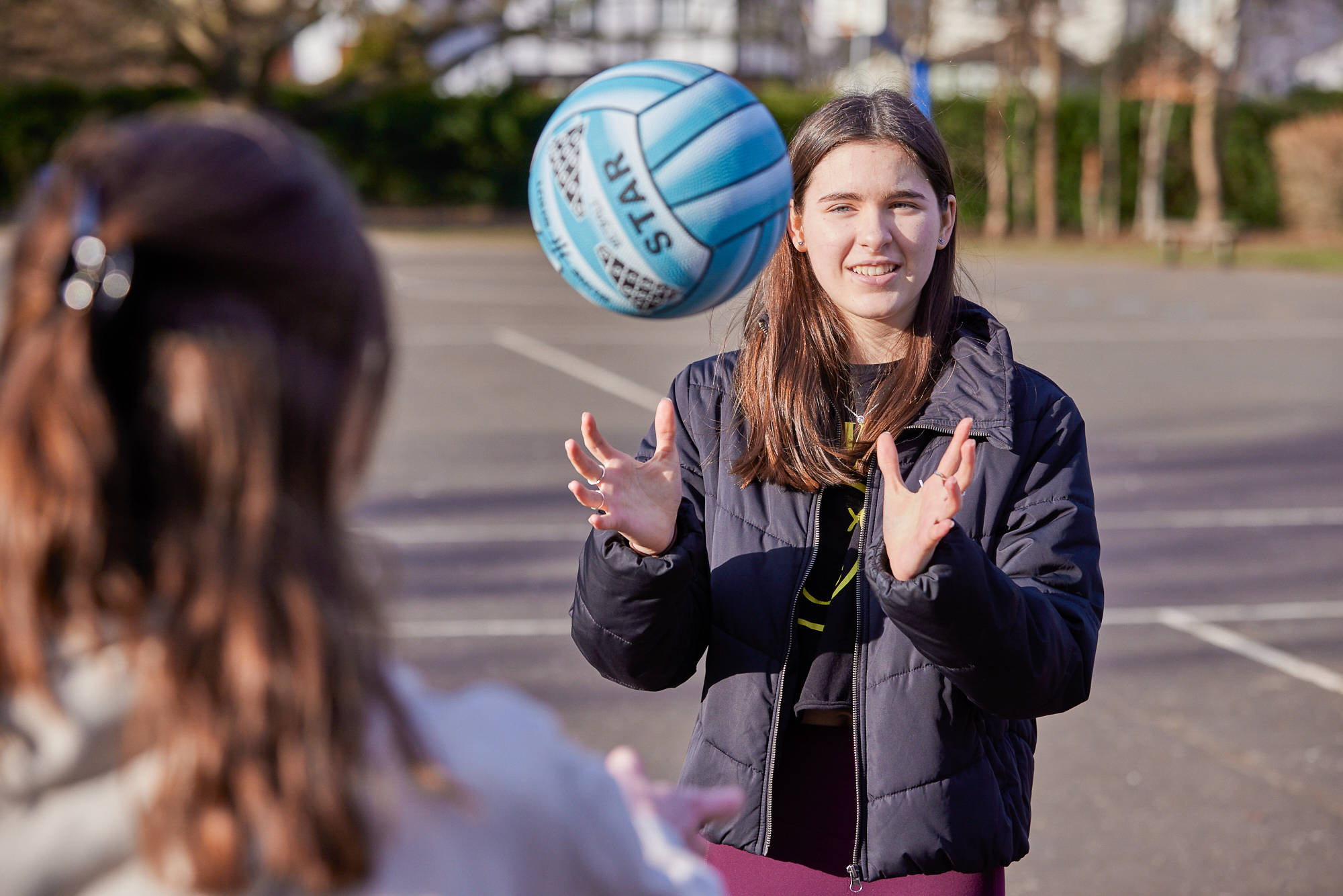 Young Person Throwing Up Ball In Playground