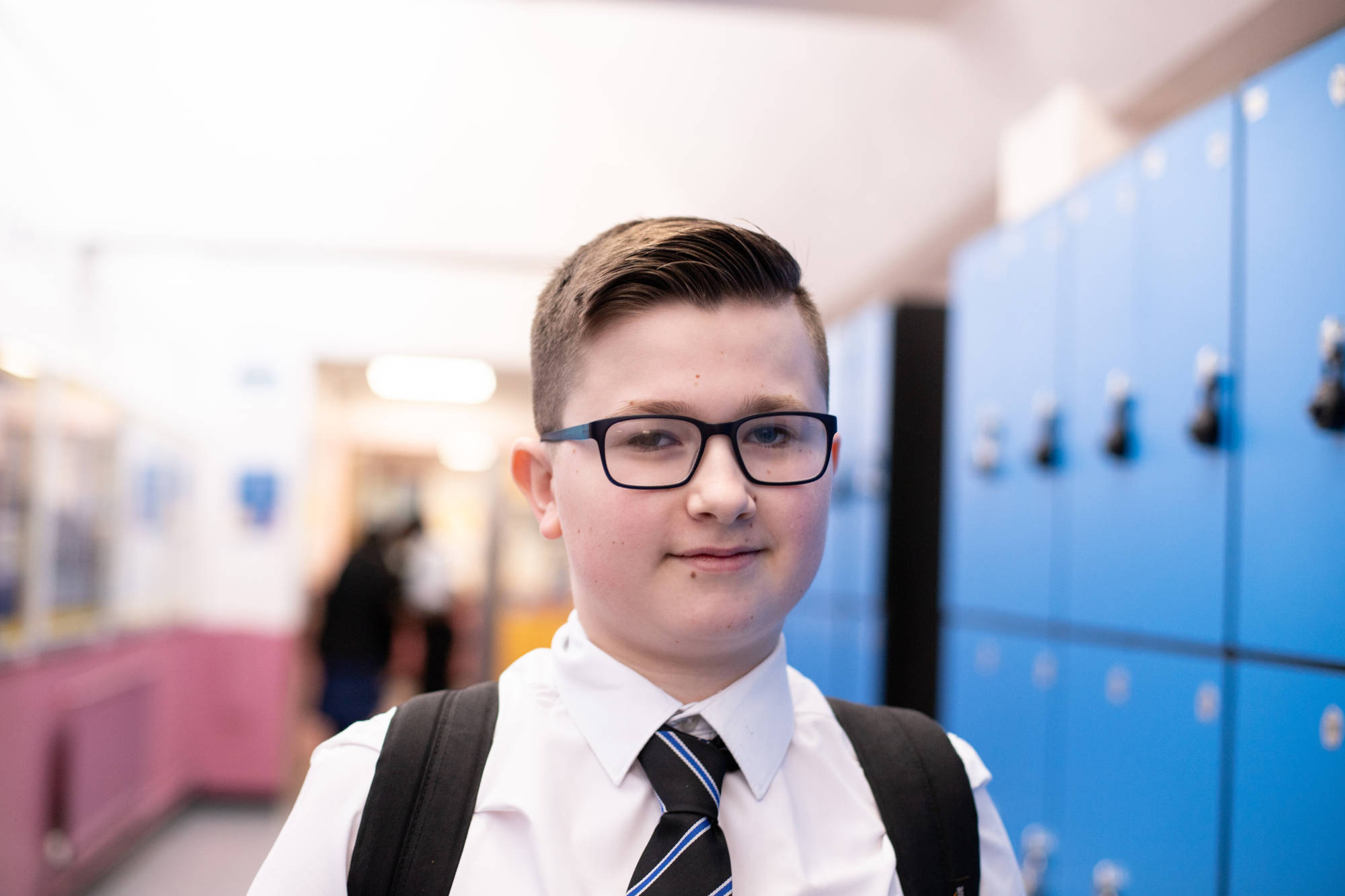Young Student Smiling At The Camera In Front Of Lockers
